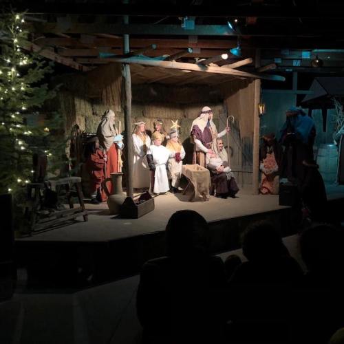 A nativity scene with figures depicting the birth of Jesus, surrounded by a rustic setting and soft lighting.