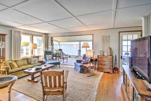 Bright, spacious living room with a mix of seating, wooden furniture, and large windows letting in natural light.