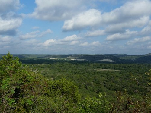 A panoramic view of lush green hills under a partly cloudy sky.