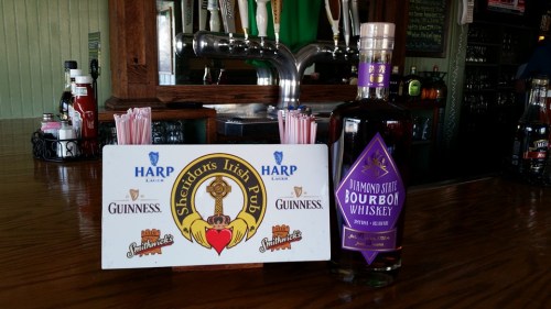 A bar scene featuring a bottle of Diamond State Bourbon Whiskey and a sign for Sheidari's Irish Pub with drink options.