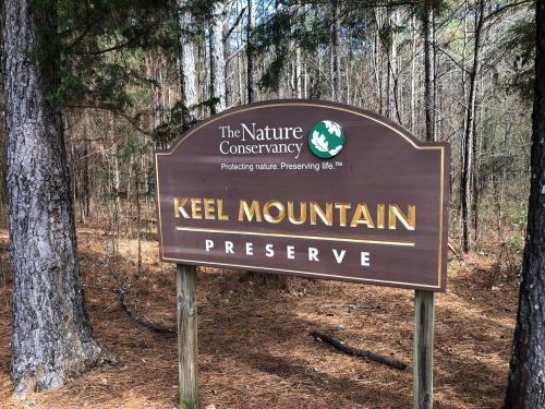 Sign for Keel Mountain Preserve by The Nature Conservancy, surrounded by trees in a natural setting.