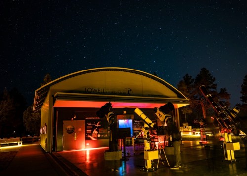 Lowell Observatory at night, featuring telescopes and a starry sky in the background.