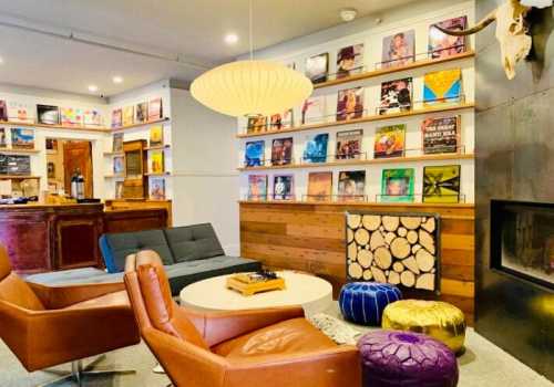 Cozy lounge area with bookshelves, a fireplace, and colorful poufs, featuring modern furniture and warm lighting.