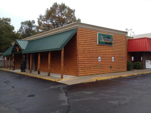 A log cabin-style building with a green roof, featuring a sign that reads "Northwoods," set in a parking lot.
