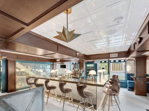 A stylish bar area with a long counter, modern stools, and elegant lighting in a well-designed interior space.