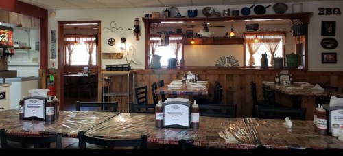 Cozy restaurant interior with wooden decor, tables set with condiments, and a warm, inviting atmosphere.