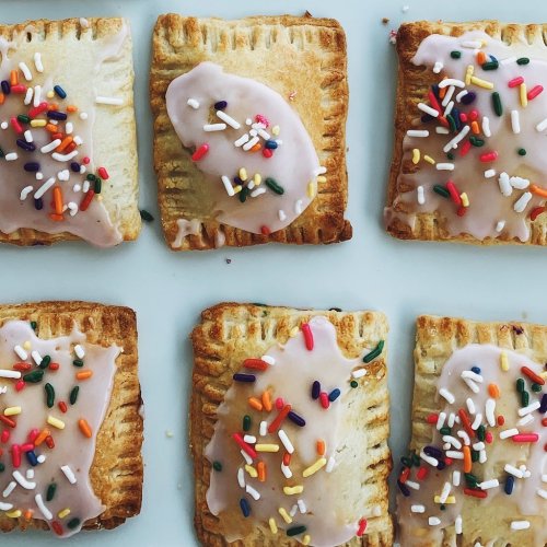 A close-up of frosted pastries topped with colorful sprinkles, arranged neatly on a white plate.
