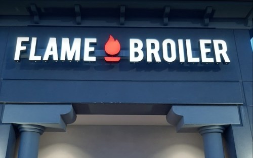 Sign for "Flame Broiler" featuring a flame icon, set against a blue background.