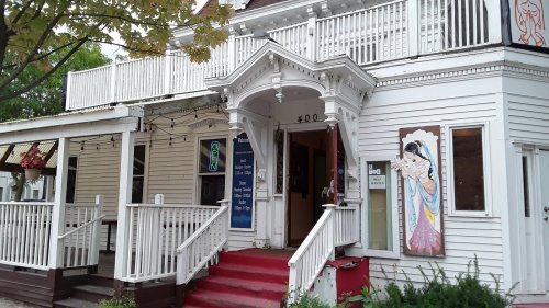 A charming white building with a red staircase, featuring a decorative entrance and colorful signage.
