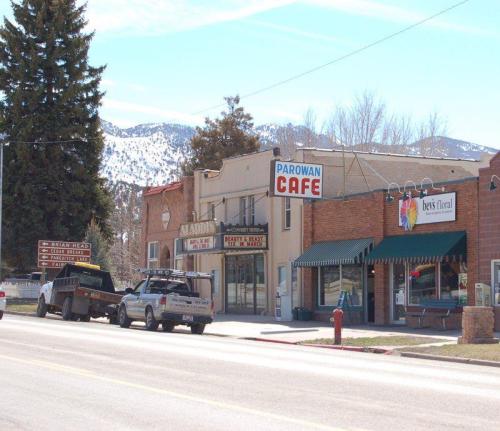 A small town street featuring the Parowan Café, shops, and mountains in the background on a clear day.