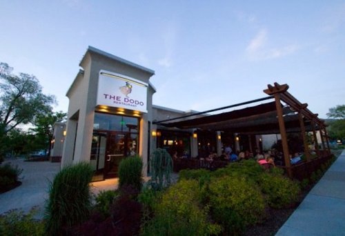 Exterior of The Dodo restaurant at dusk, featuring outdoor seating and lush landscaping.