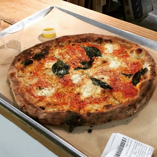 A freshly baked pizza with melted cheese, tomato sauce, and fresh basil on a wooden table.