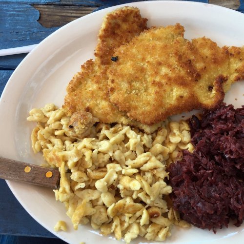 A plate featuring golden fried fish, creamy macaroni and cheese, and a side of red cabbage.
