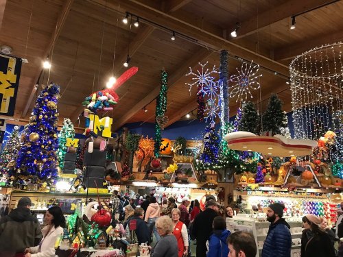A festive store filled with colorful Christmas decorations, lights, and shoppers enjoying the holiday atmosphere.