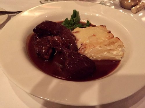 A plate featuring tender beef in rich sauce, accompanied by creamy mashed potatoes and a garnish of greens.