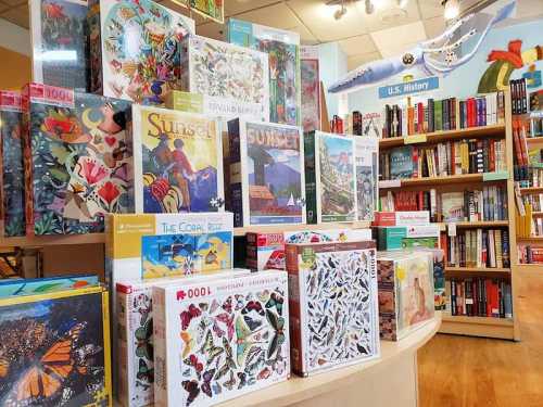 A display of colorful jigsaw puzzles in a bookstore, with bookshelves in the background.