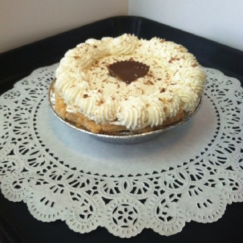 A creamy pie topped with whipped cream and chocolate shavings, sitting on a decorative lace doily.