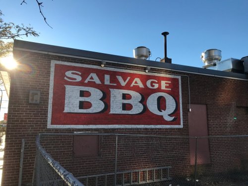 A brick wall featuring a large sign that reads "SALVAGE BBQ" in bold red and white letters.