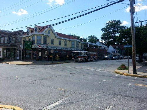 A street view featuring a yellow building, a fire truck, and power lines under a clear blue sky.
