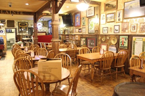 Cozy restaurant interior with wooden tables and chairs, decorated walls featuring framed pictures and memorabilia.