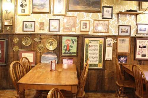 Cozy restaurant interior with wooden tables and walls adorned with framed photos and decorative plates.