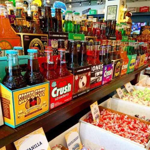 A colorful display of various soda bottles and candy in a shop, showcasing different flavors and brands.