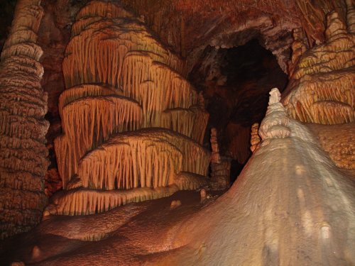 Stalactites and stalagmites in a dimly lit cave, showcasing intricate formations and textures.