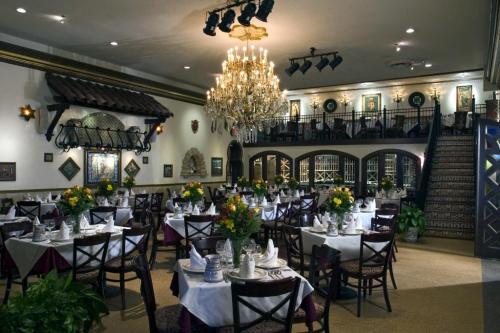 Elegant restaurant interior with chandeliers, floral centerpieces, and neatly arranged tables. Warm, inviting atmosphere.