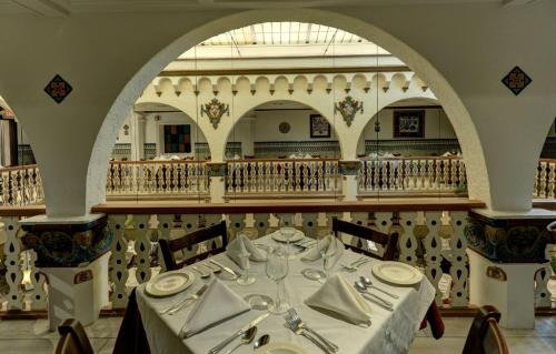 Elegant dining setup with a white tablecloth and neatly arranged tableware, framed by arched architecture in a restaurant.