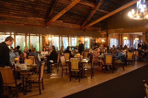 A cozy restaurant interior with wooden beams, filled with diners at tables and warm lighting.