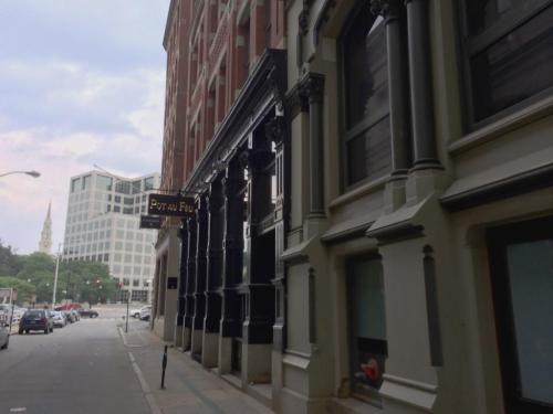 Street view featuring a building with "Pot au Feu" sign, alongside modern architecture in the background.
