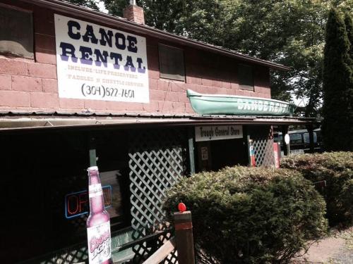 A rustic building with a "Canoe Rental" sign, featuring a green canoe on the roof and a general store entrance.