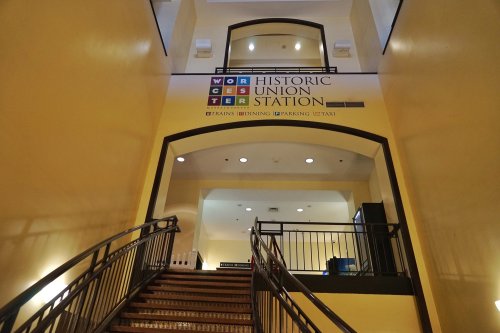 Interior view of Worcester Union Station, featuring a staircase and signage for trains, dining, parking, and taxis.
