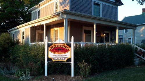 A charming house with a porch and a sign reading "Vintage Charm Guest House" in front.