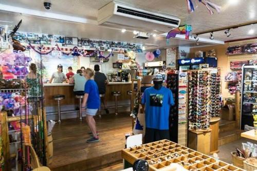 A vibrant shop interior with customers browsing, displaying sunglasses, souvenirs, and colorful decorations.