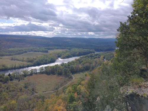 A scenic view of a river winding through lush green hills under a cloudy sky.