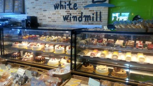 Display case filled with various cakes and pastries at a bakery called "White Windmill."