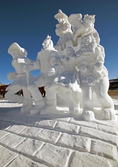 A large snow sculpture featuring several characters in a dynamic pose against a clear blue sky.