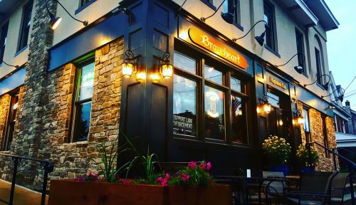 A cozy pub exterior with stone walls, warm lighting, and flower planters, set in an inviting evening atmosphere.