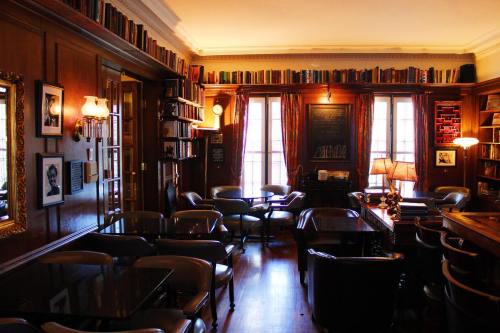 Cozy library interior with wooden walls, bookshelves, and tables, illuminated by warm lighting and large windows.