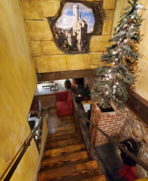 A staircase leading down to a cozy space with a painted castle mural and a decorated Christmas tree.