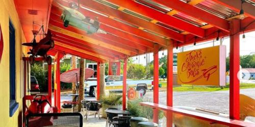 Colorful outdoor seating area of a diner with red beams, vintage decor, and a sign reading "Jack's Classic Dots."