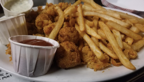 A plate of crispy fried food featuring French fries, two dipping sauces, and golden-brown bite-sized pieces.