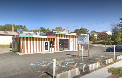 Colorful striped building with a drive-thru, surrounded by a parking lot and trees in the background.