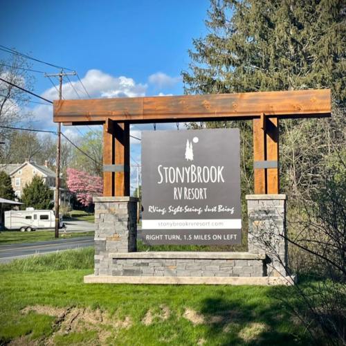 Sign for StonyBrook RV Resort with directions, surrounded by greenery and trees.