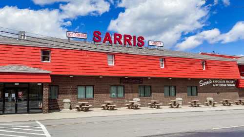 Exterior of Sarris Ice Cream and Candies, featuring a red building with picnic tables and a blue sky.