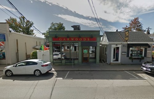 A storefront labeled "Garwoods" with a green facade, surrounded by other buildings and parked cars on a street.