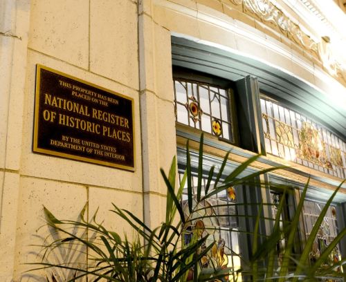 Plaque indicating the property is on the National Register of Historic Places, with decorative stained glass in the background.