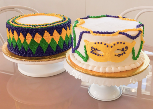 Two colorful cakes decorated for a celebration, one with a mask design and the other featuring a diamond pattern.