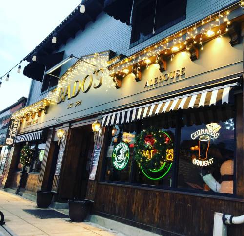 Exterior of Bado's Alehouse, featuring festive lights and neon signs, with a welcoming atmosphere.